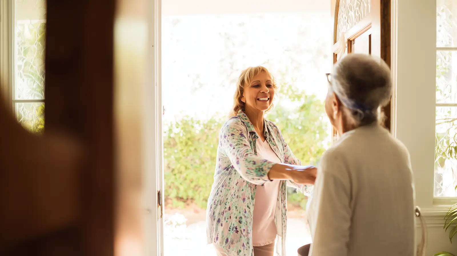 Caregiver greeting senior at home